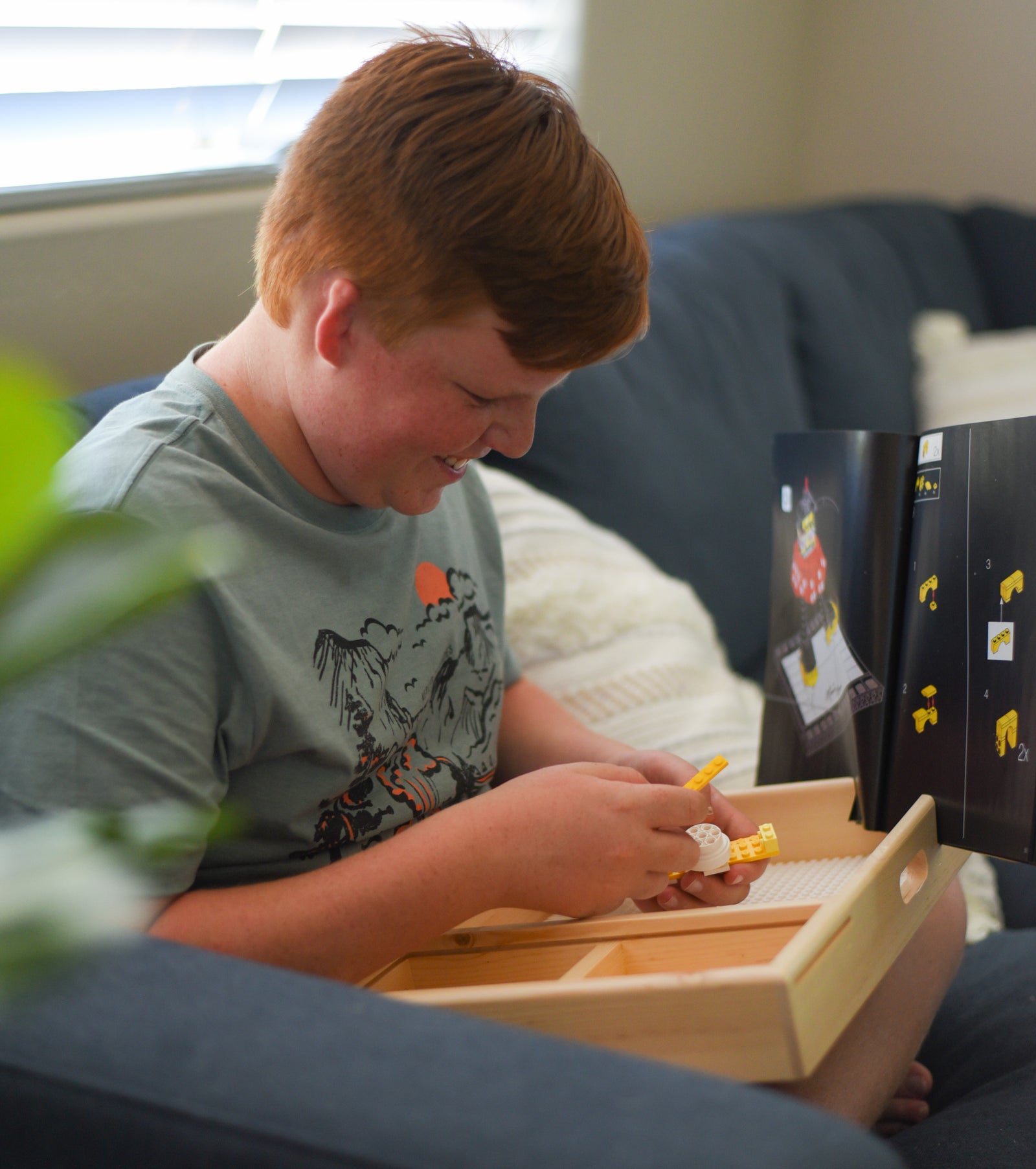 Boy building a LEGO set on a wood LEGO tray 